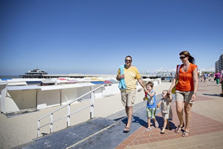 A summer family with children walks along the seawall.